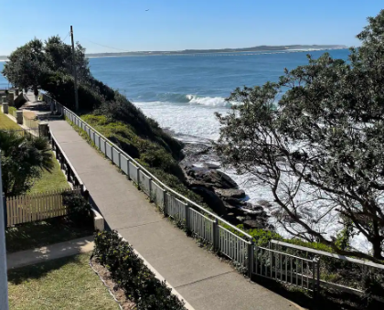 A concrete walkway leading to the ocean on a sunny day