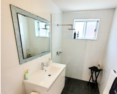 A bathroom with a sink a mirror and a walk in shower