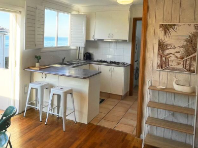 A kitchen with white cabinets and stools and a picture on the wall.
