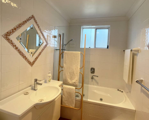 A bathroom with a sink , bathtub and mirror.