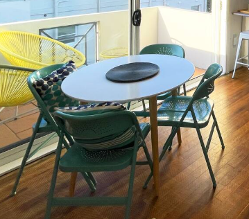 A table and chairs on a balcony with a yellow chair in the background