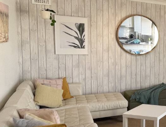 A living room with a couch and a round mirror on the wall.