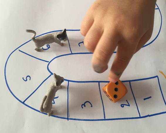 A child is playing a board game with cats and dice
