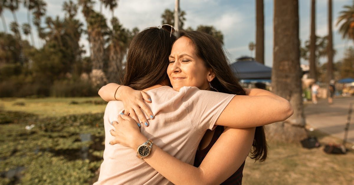 Two women are hugging each other in a park.