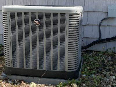 Gray Rheem air conditioner unit outside a house.