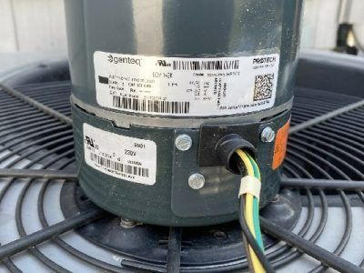 Close-up of an AC unit motor with attached wires. The motor is dark green, mounted on a fan.