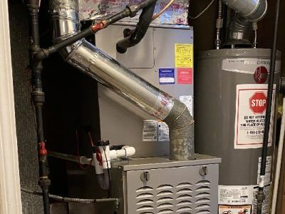 Furnace and water heater in a utility room. Metal pipes, ducts and a 