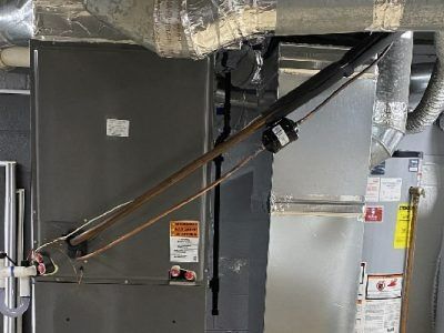 HVAC system with ductwork and a gray furnace unit. A copper pipe and black conduit are visible.