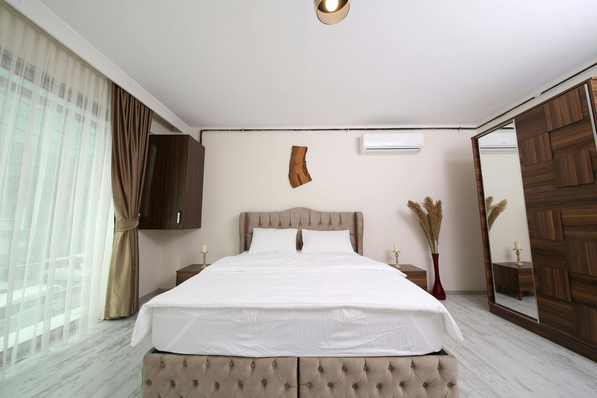 A bedroom with a large bed, wooden wardrobe, and a window with curtains.