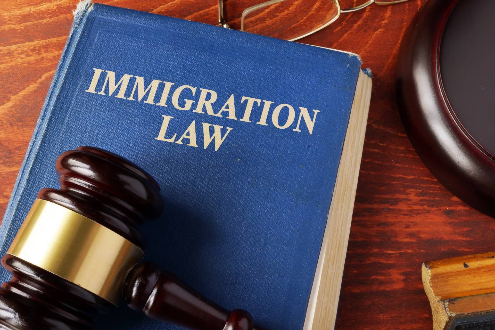 A blue book titled immigration law is on a wooden table next to a judge 's gavel.