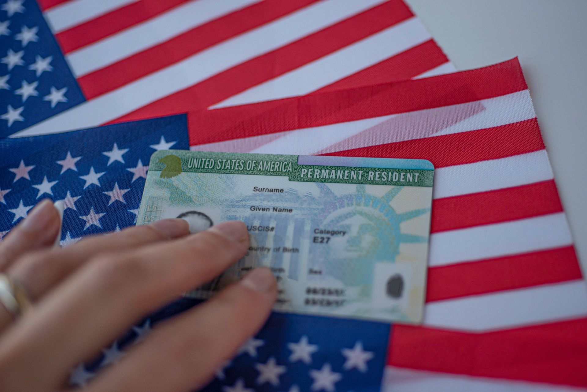 A person is holding a green card in front of an american flag.