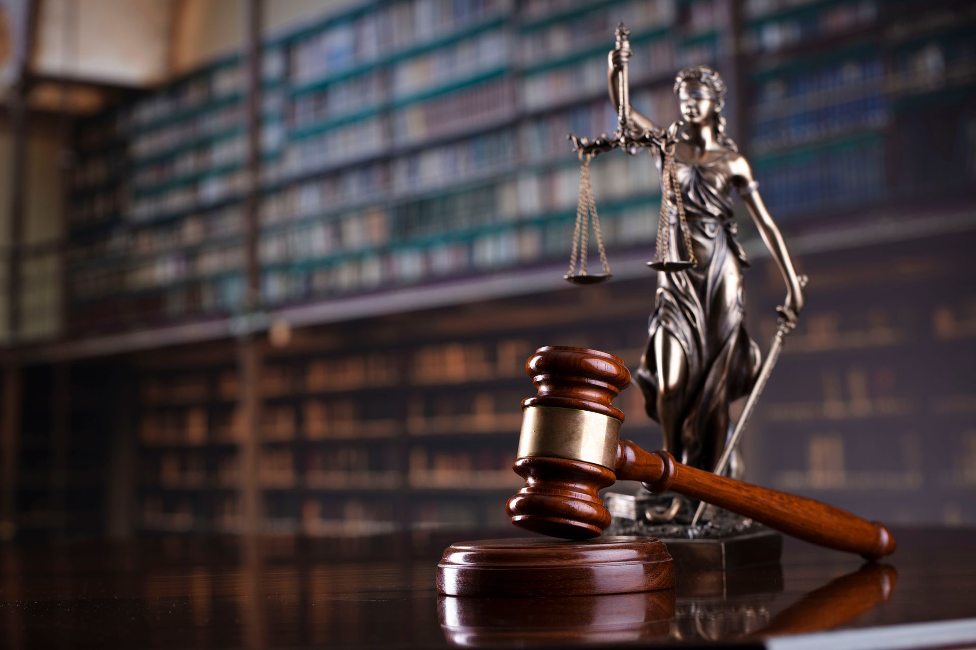 A statue of justice is sitting next to a judge 's gavel in a courtroom.