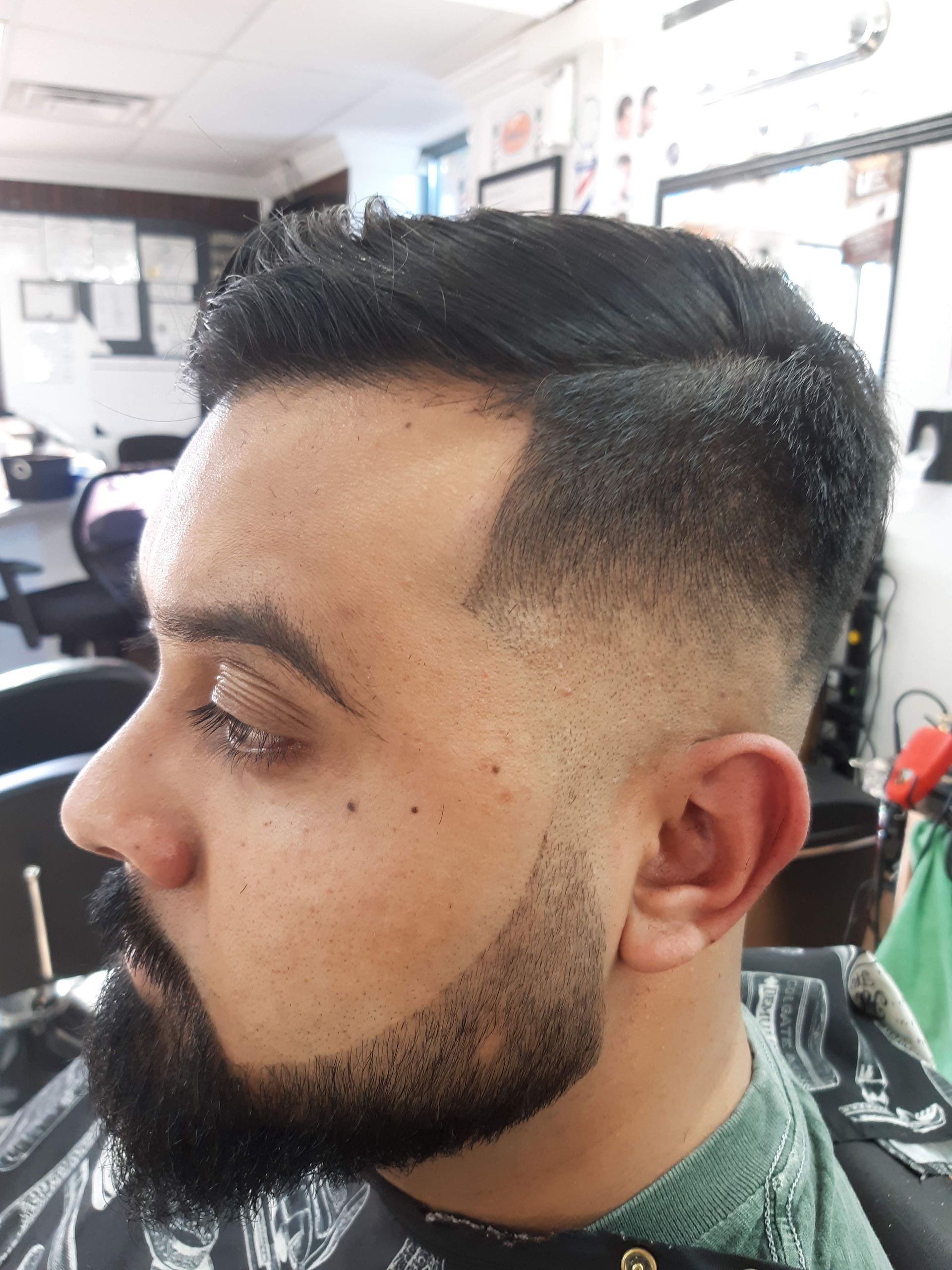 A man with a beard is getting his hair cut at a barber shop.