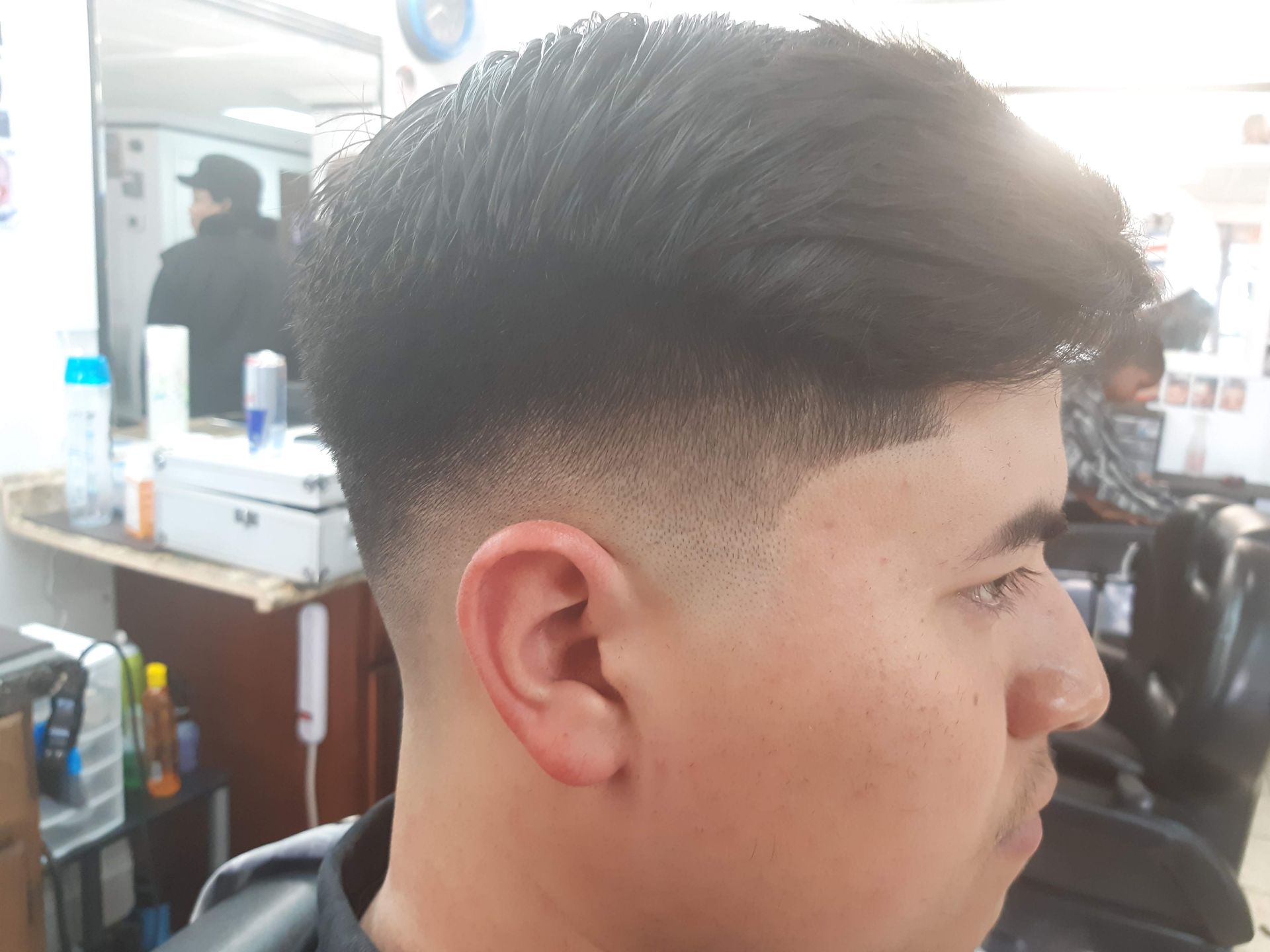 A young man is getting his hair cut at a barber shop.