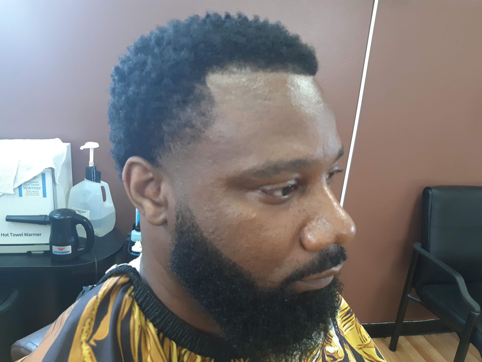 A man with a beard is getting his hair cut at a barber shop.