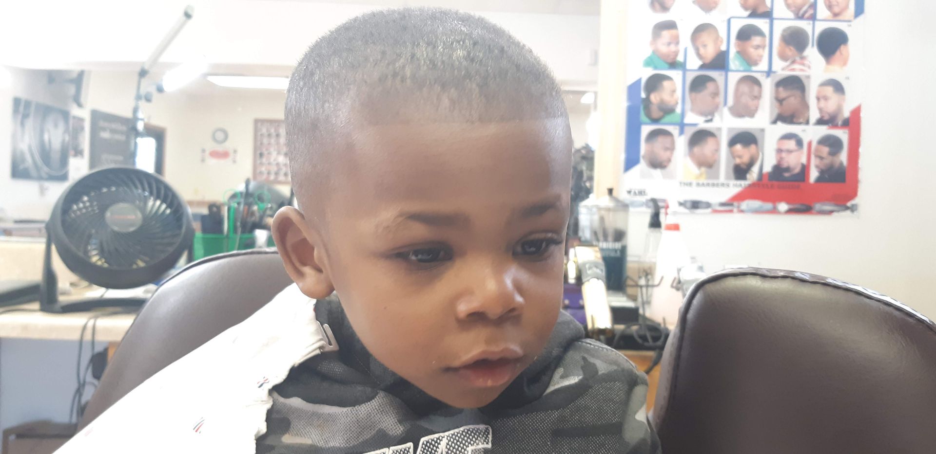 A young boy is getting his hair cut at a barber shop.