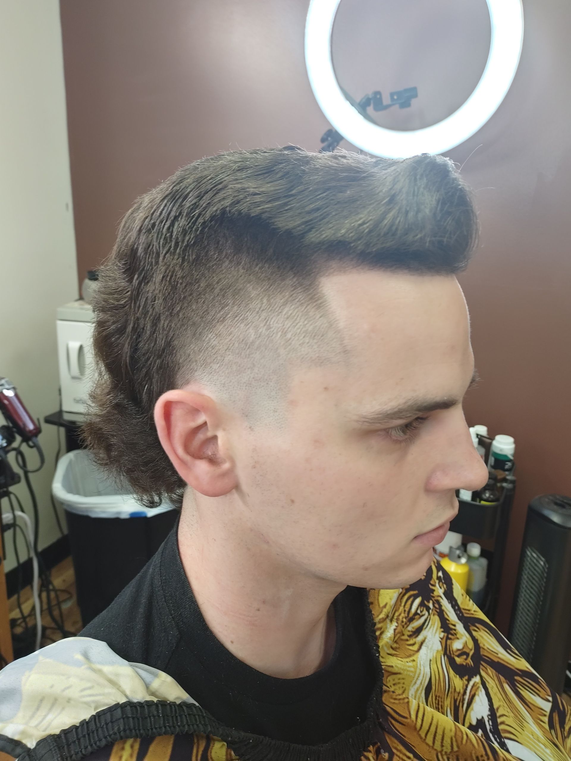 A man is getting his hair cut at a barber shop.