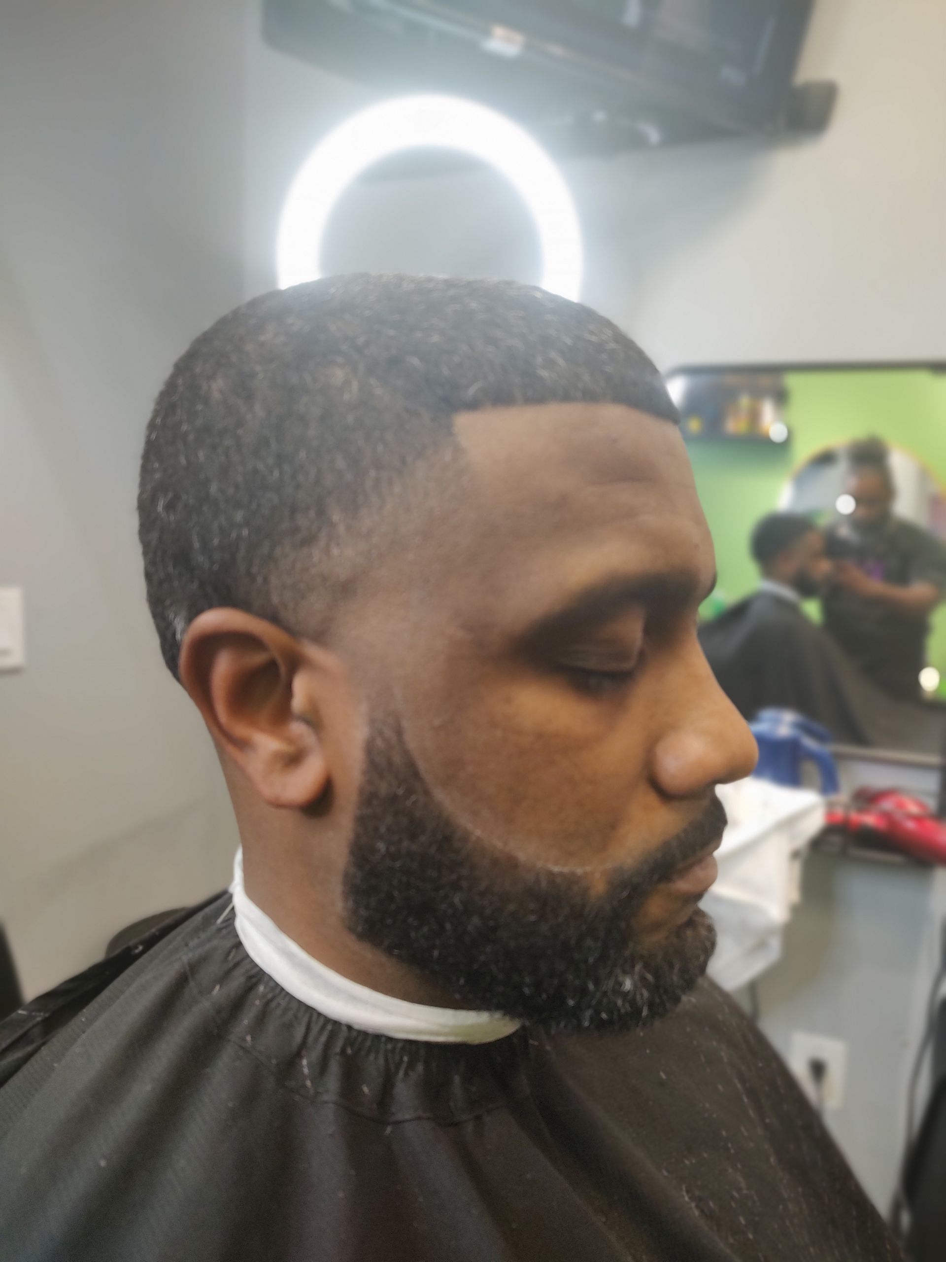 A man with a beard is getting his hair cut at a barber shop