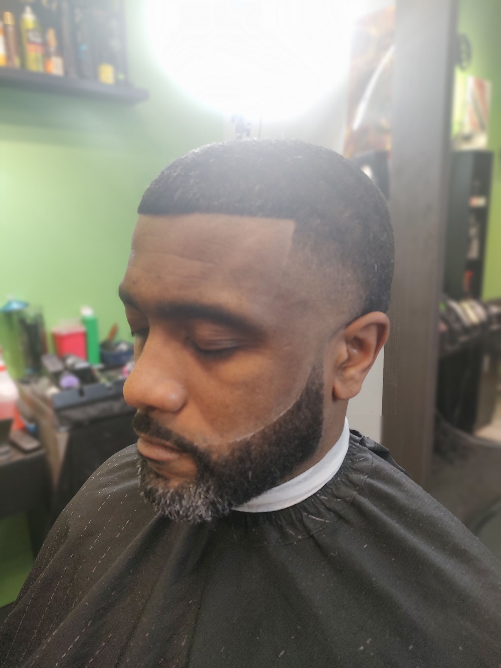 A man with a beard is getting his hair cut at a barber shop.