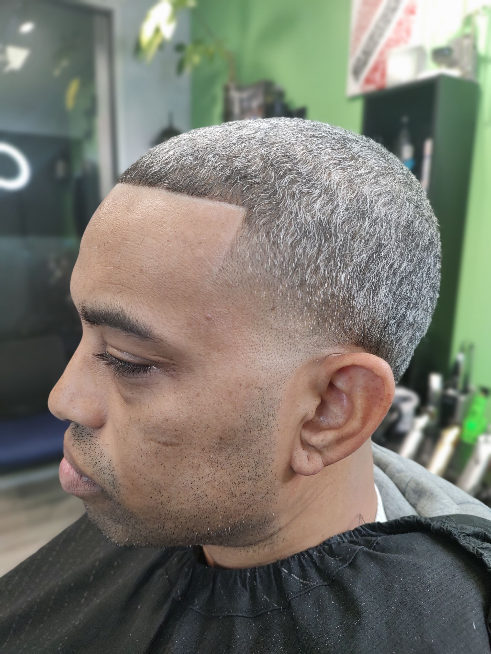 A man is getting his hair cut at a barber shop.