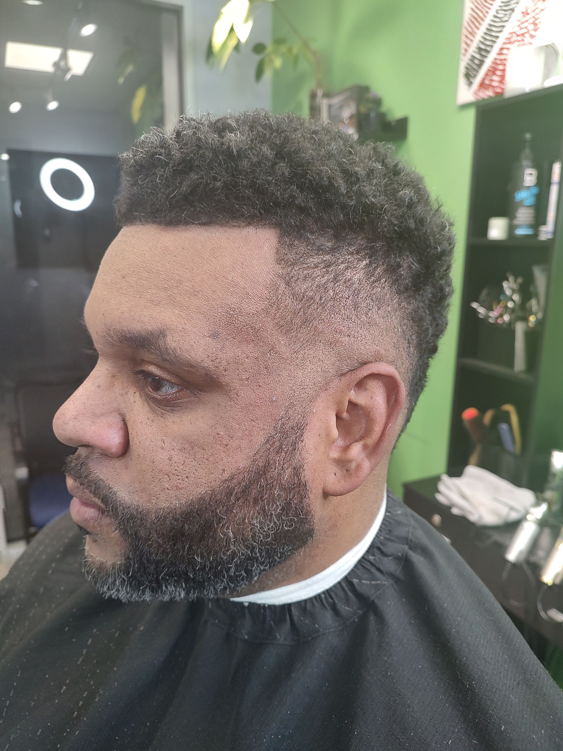 A man with a beard is getting his hair cut at a barber shop.