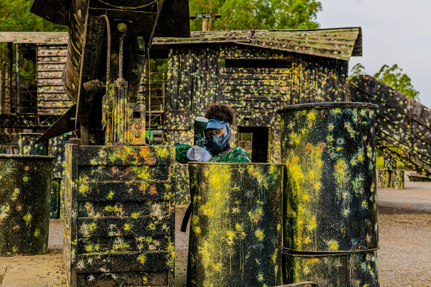 Um homem mascarado está jogando paintball em um campo.