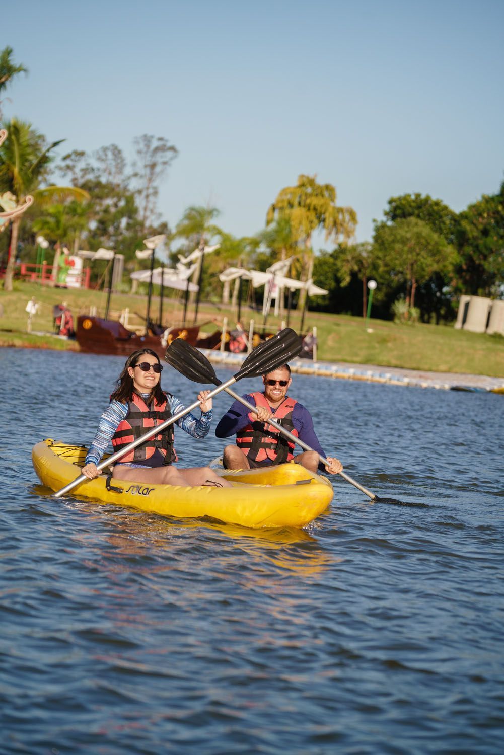 Um homem e uma mulher estão remando em caiaques em um lago.