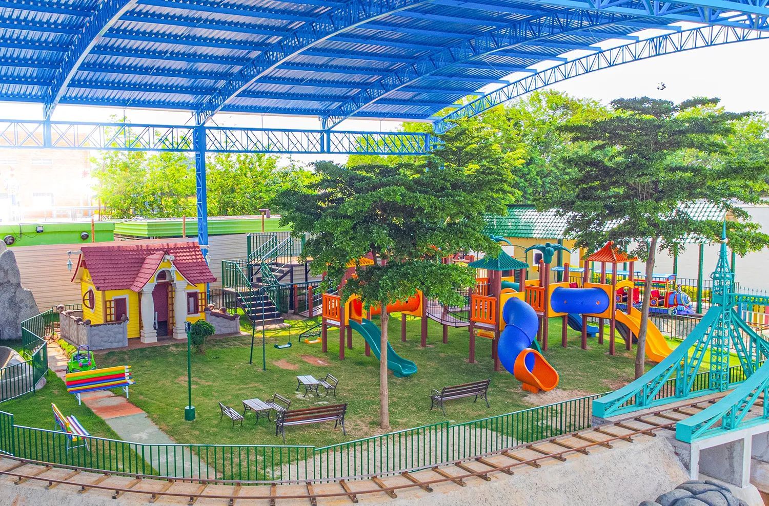 Um playground com uma linha de trem passando por ele e um telhado azul.