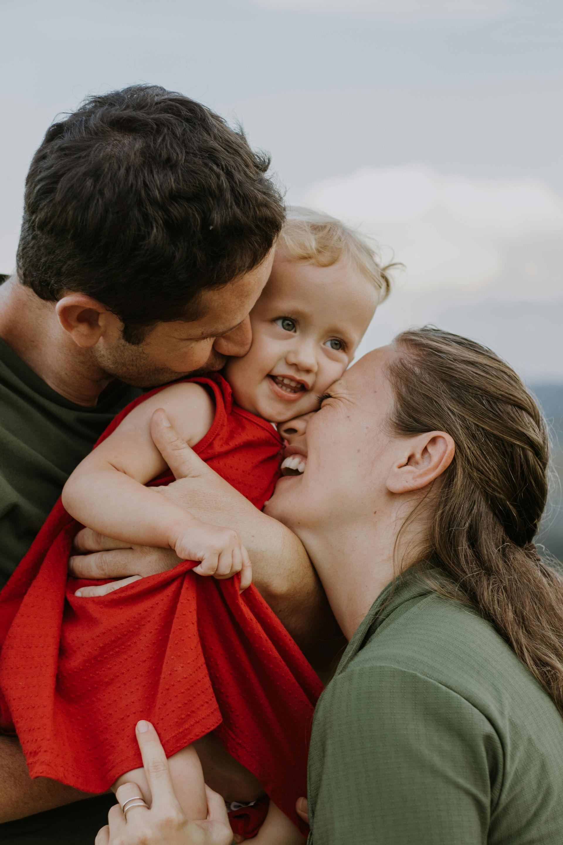 A man and a woman are holding a little girl in their arms.