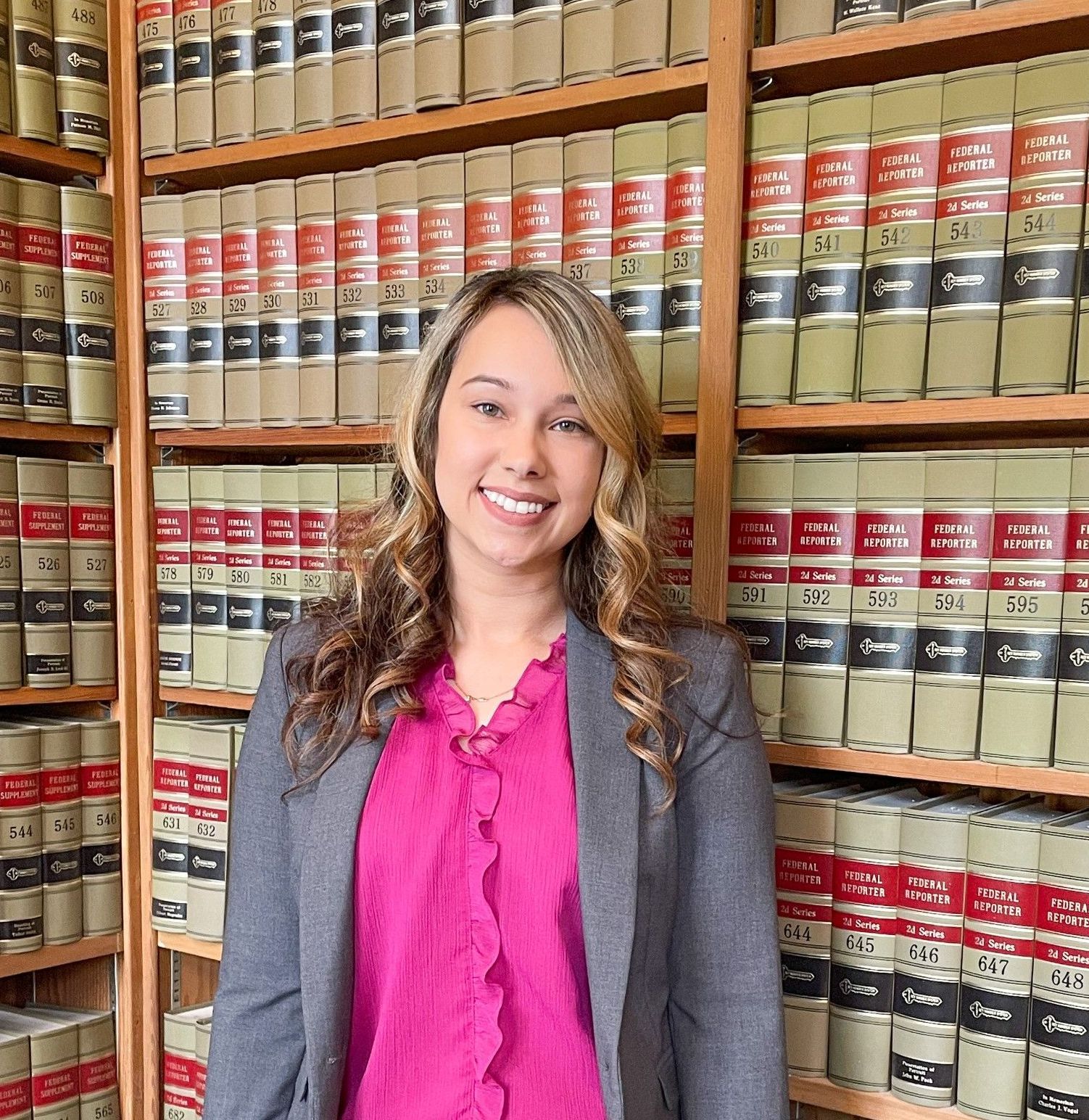 A woman is standing in front of a bookshelf in a library.