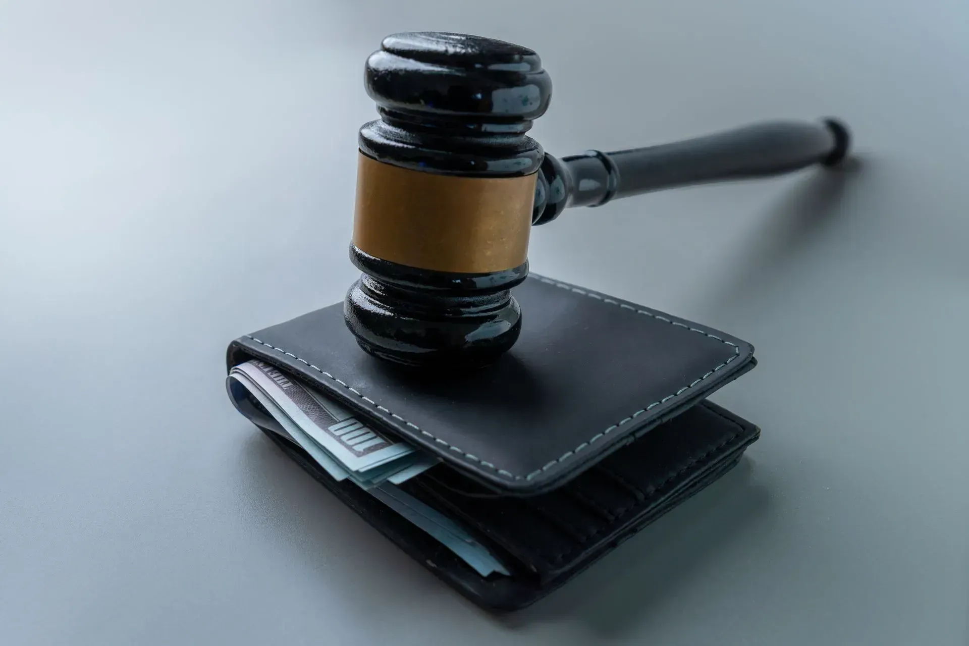 Gavel resting on a black wallet with cash peeking out, symbolizing legal or financial judgment