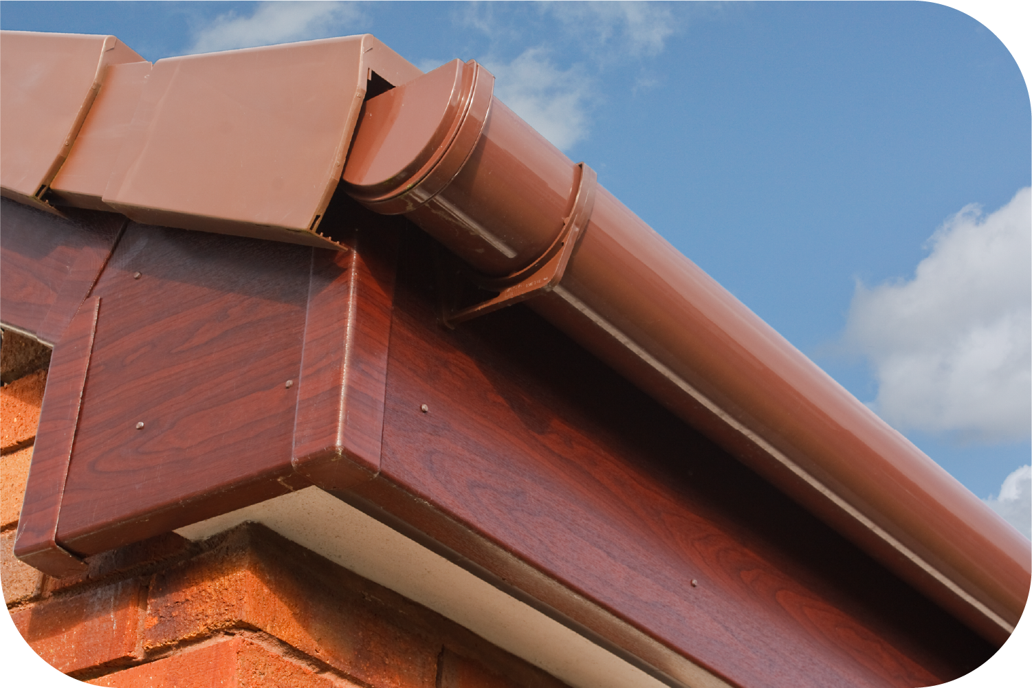 A brown gutter on the side of a brick building