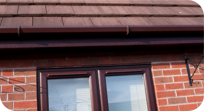 A brick building with a window and a brown gutter