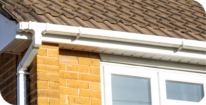 A house with a brown tiled roof and a white gutter.