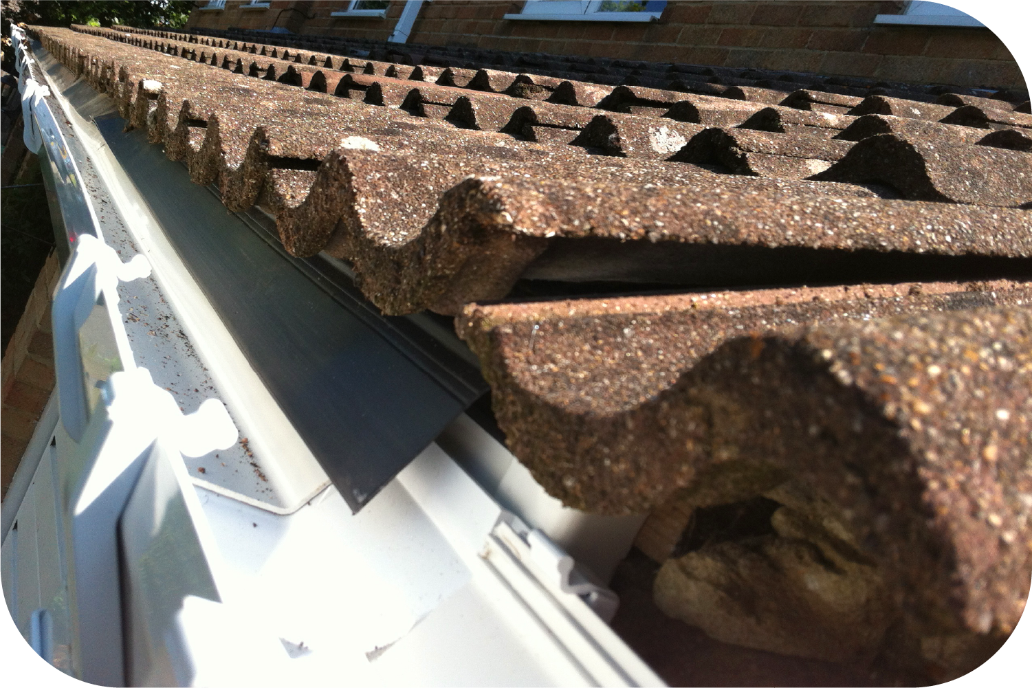 A close up of a gutter with a roof in the background