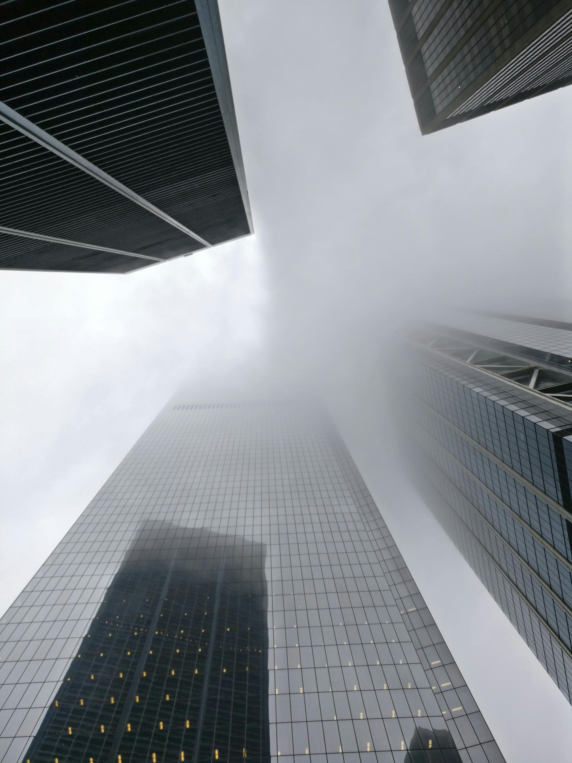 Skyscrapers reaching into a cloudy sky; gray, silver, and black buildings.