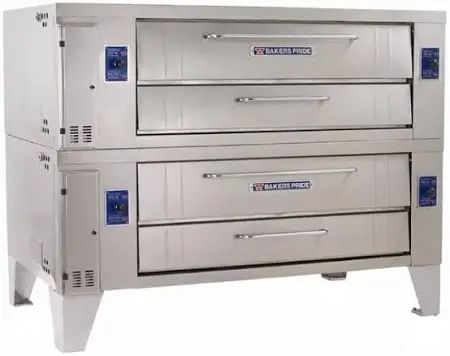 Three pizzas with toppings on a rack inside a commercial pizza oven.