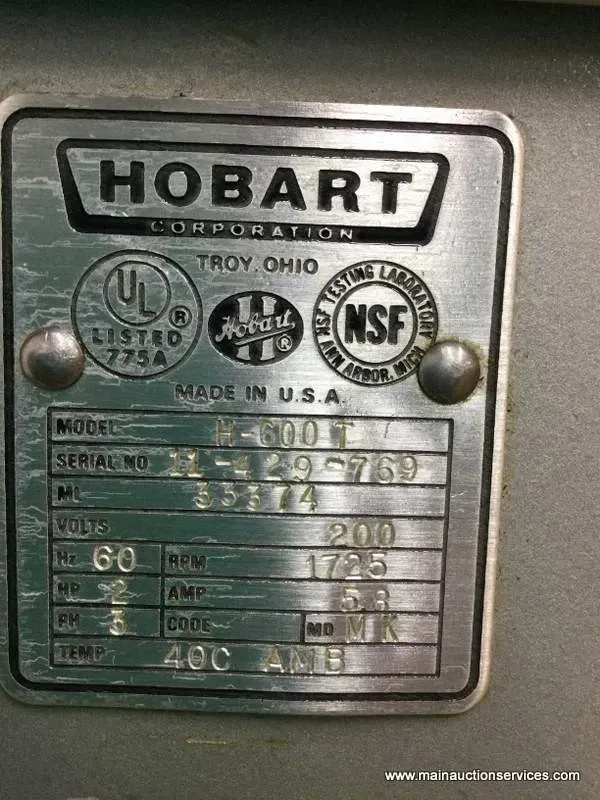 Baker placing loaves of bread into a commercial oven with a peel. Stainless steel, warm interior.