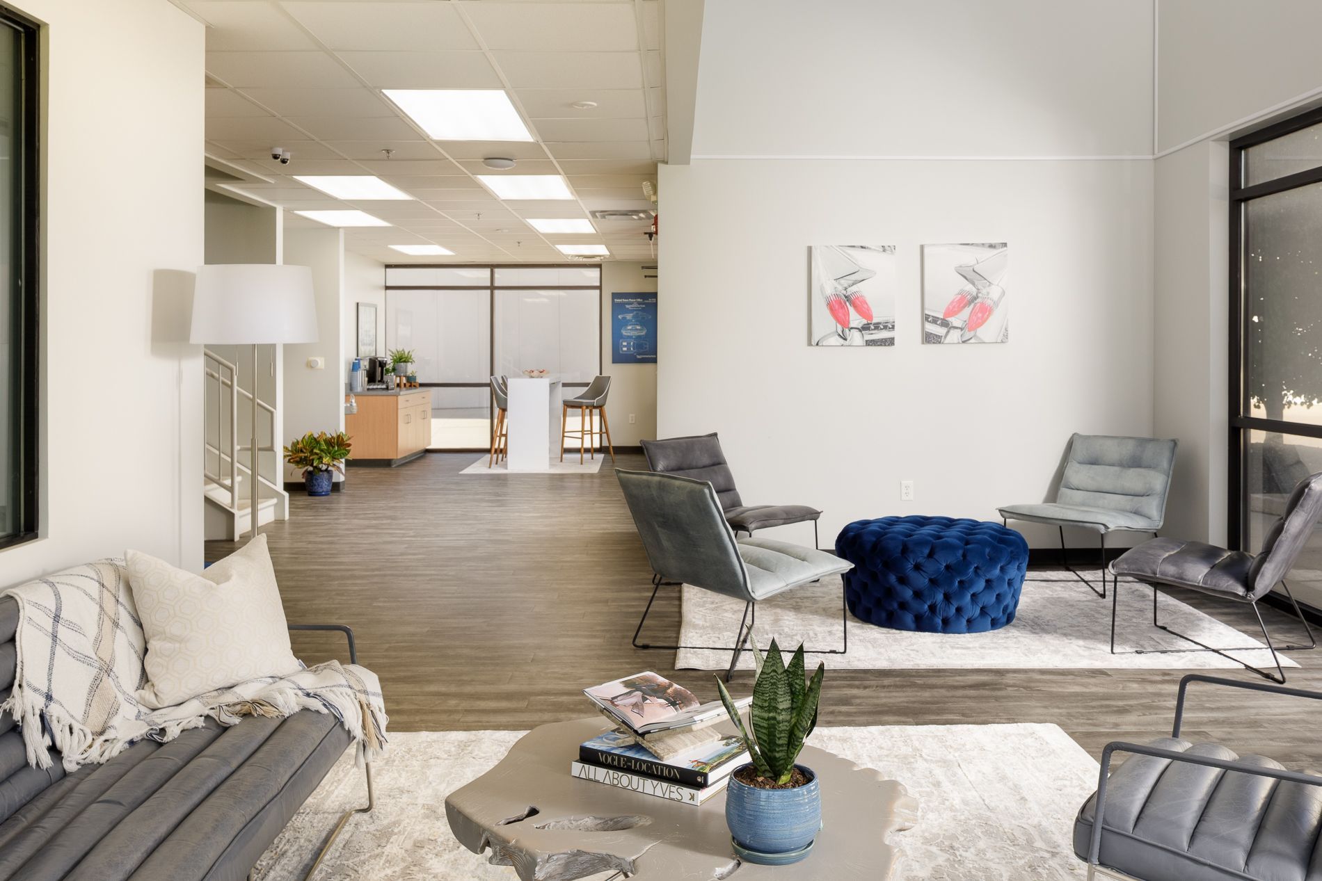 Modern office waiting area with gray furniture, artwork, and a fluffy blue ottoman.