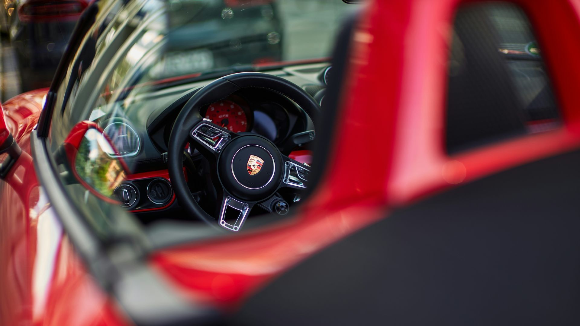 Red Porsche sports car interior with black steering wheel.