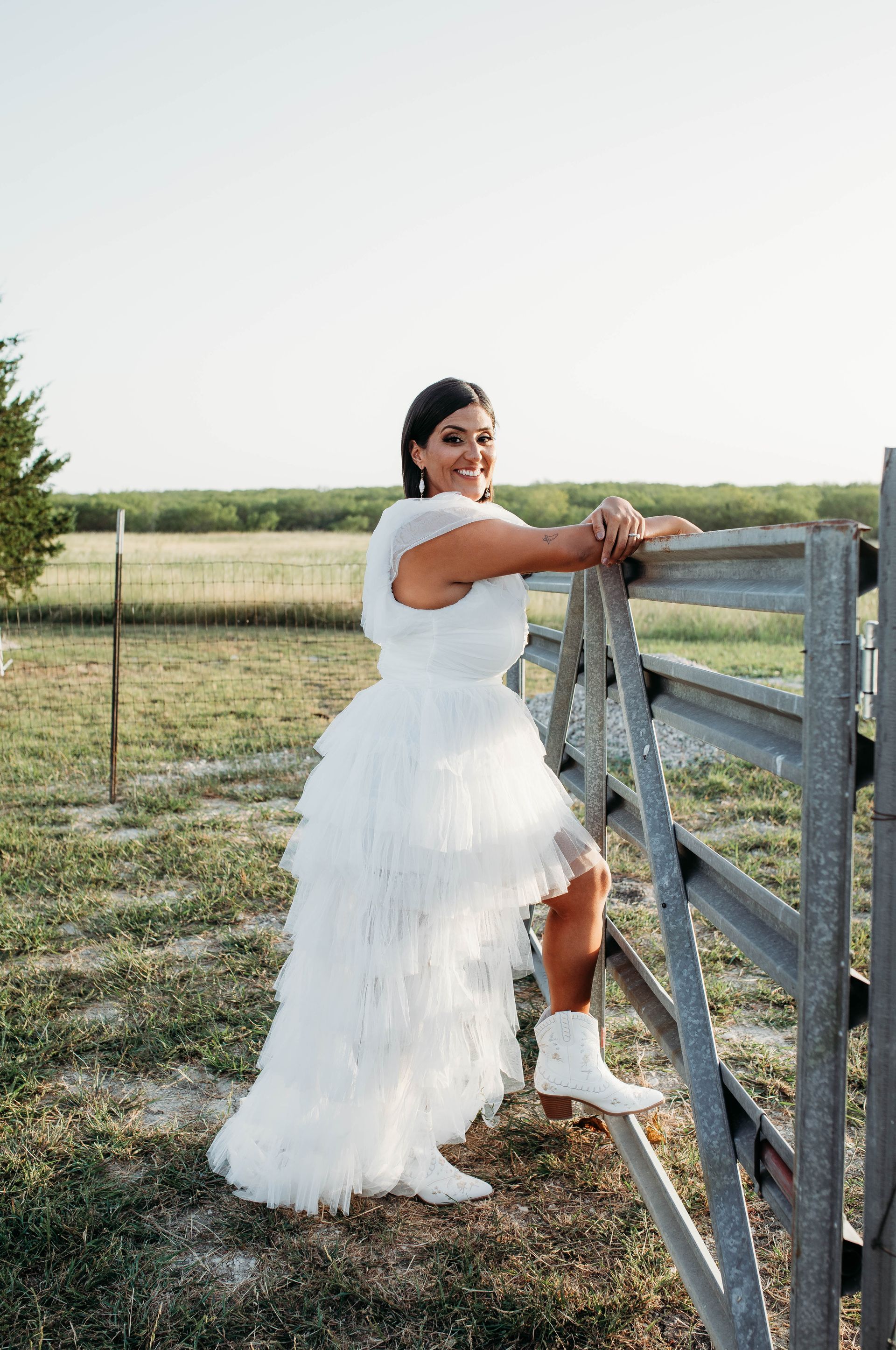 A woman in a white dress leaning on a fence