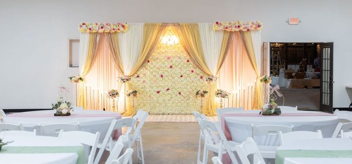 A wedding venue with white chairs and floral decorations
