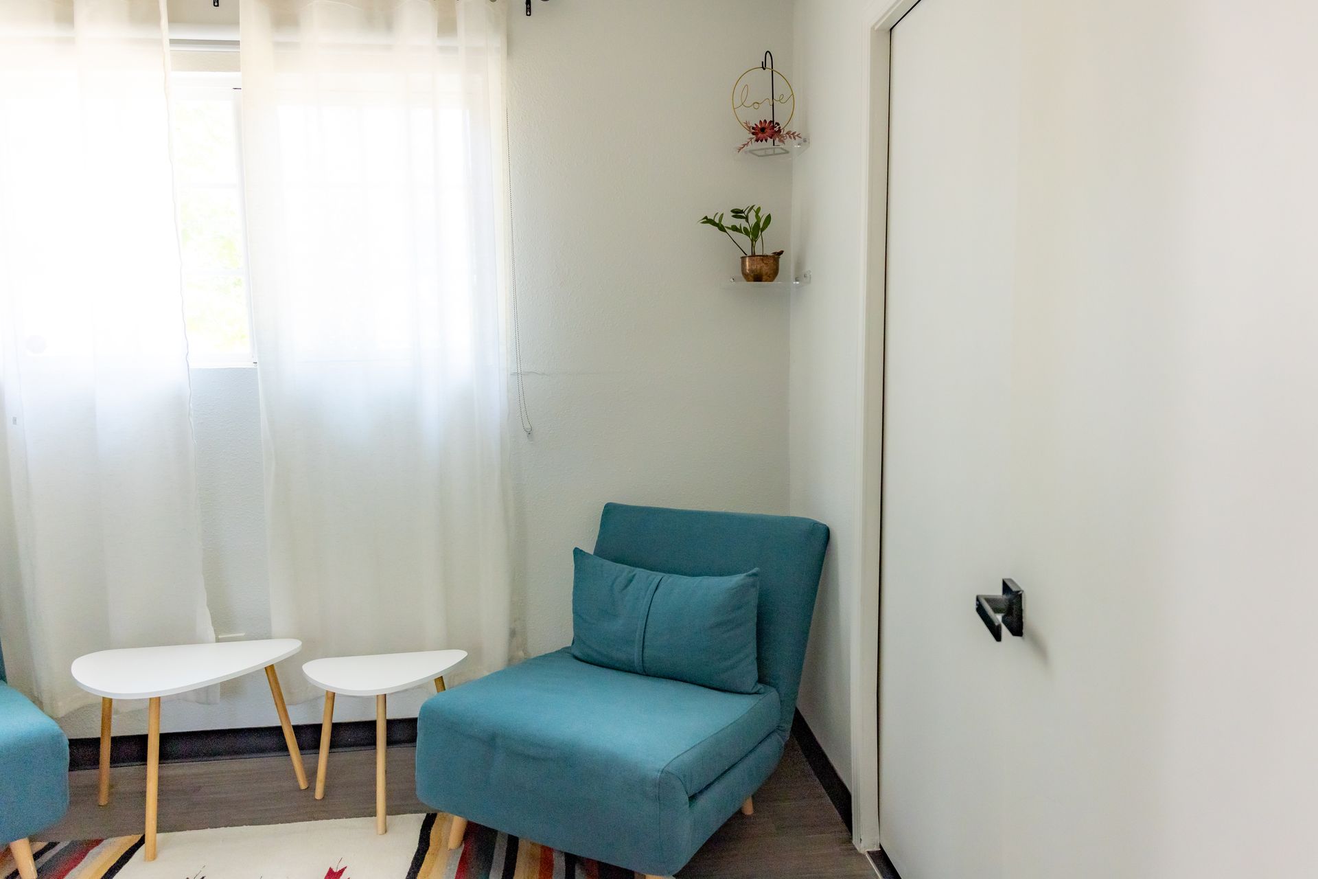 Guest room at MAHA ATX with a blue chair and a white tables