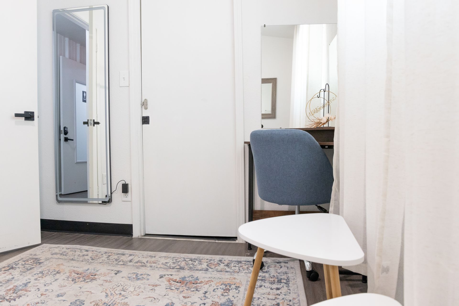 Guest room setup at MAHA ATX with a couch, desk, and a mirror on the wall