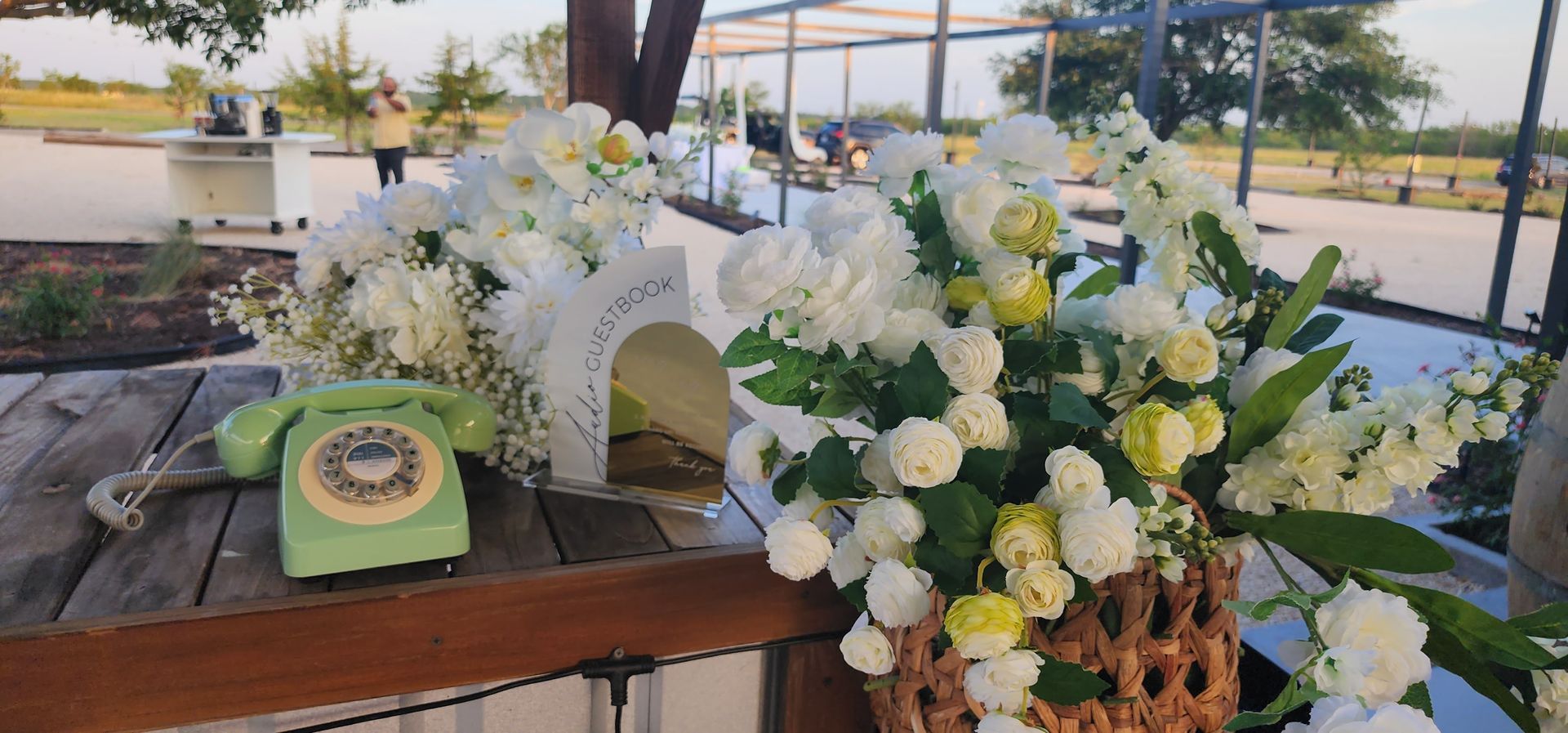 A basket of flowers and telephone sitting on a wooden table during an event in MAHA ATX