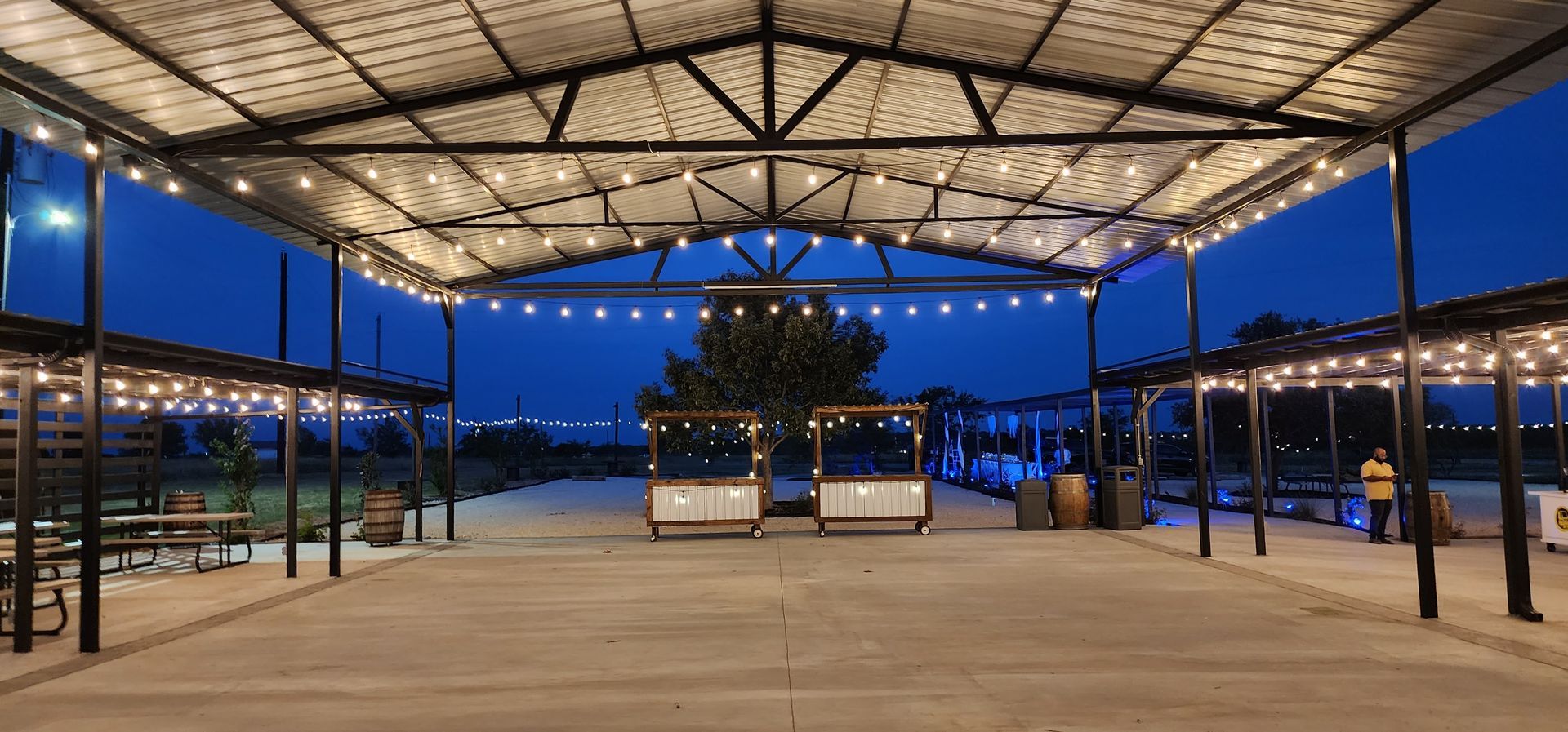 A covered event venue with benches and string lights