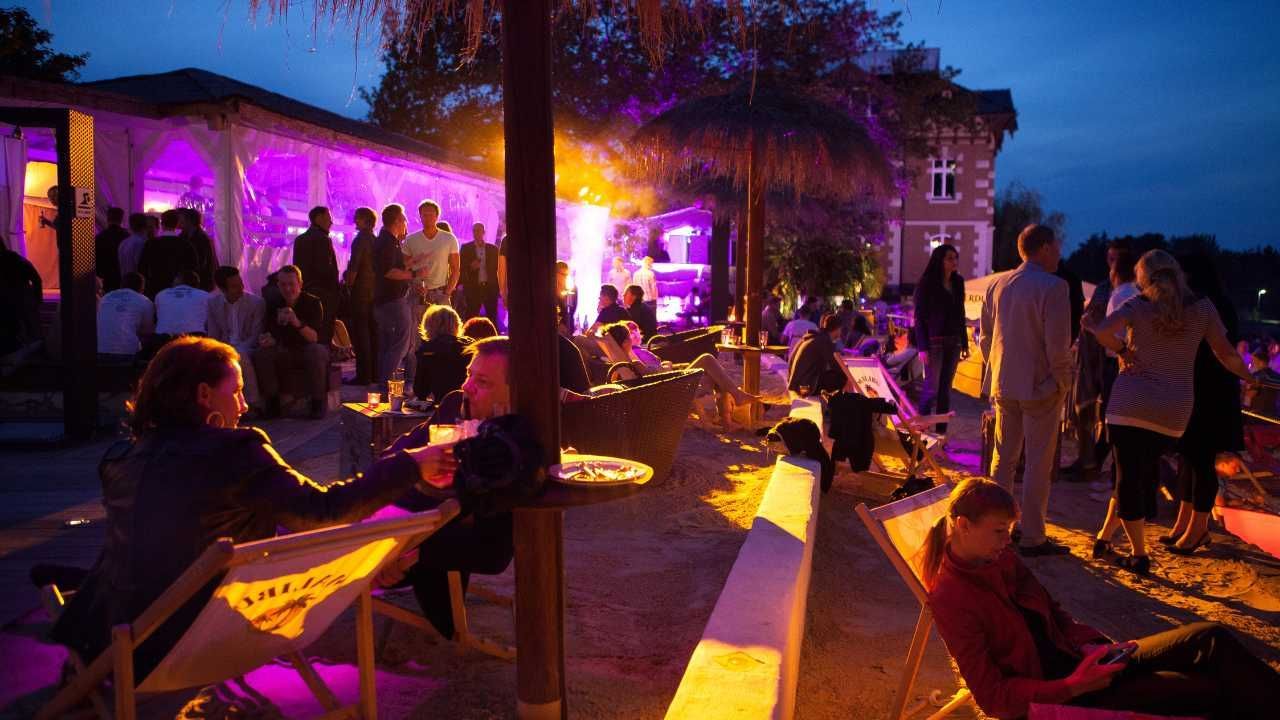 A nighttime gathering with people in chairs and umbrellas.