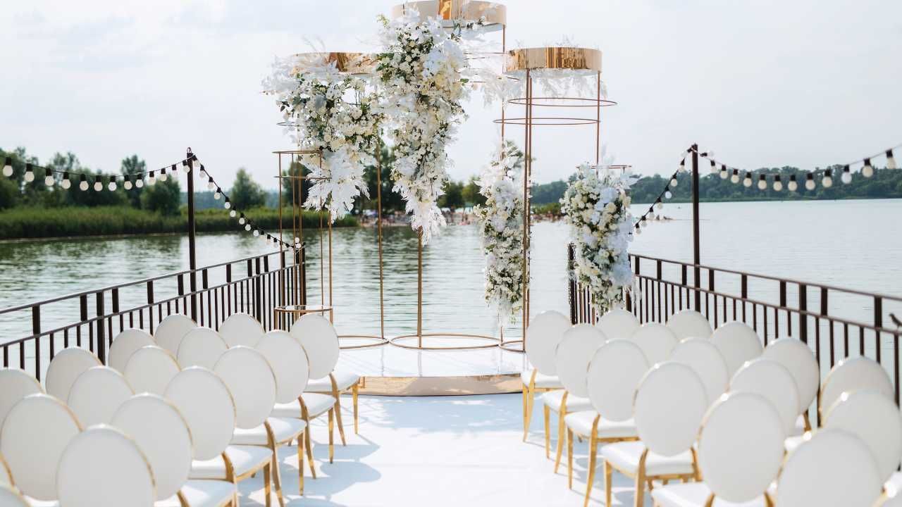 A picturesque wedding ceremony on the water, featuring elegant white chairs.