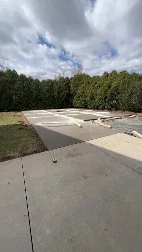 Concrete patio with surrounding greenery, cloudy sky.