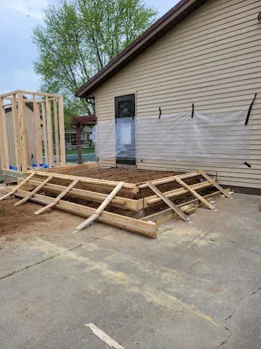 Wood frame construction of a ramp and small room addition next to a house.